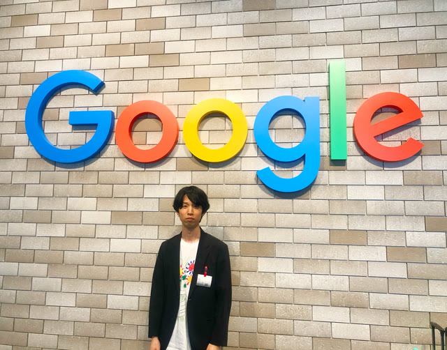 Googleのロゴ看板の前に立つ川合